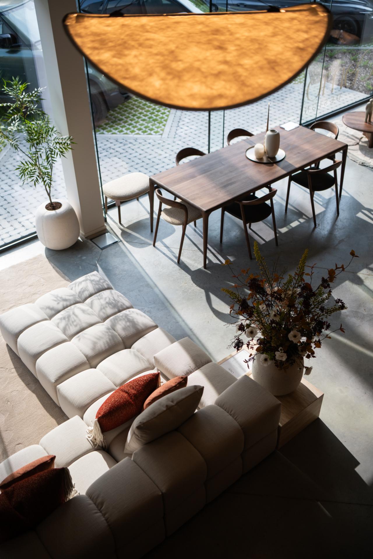 Houten eettafel met designstoelen en grote raampartijen in eigentijdse woning
