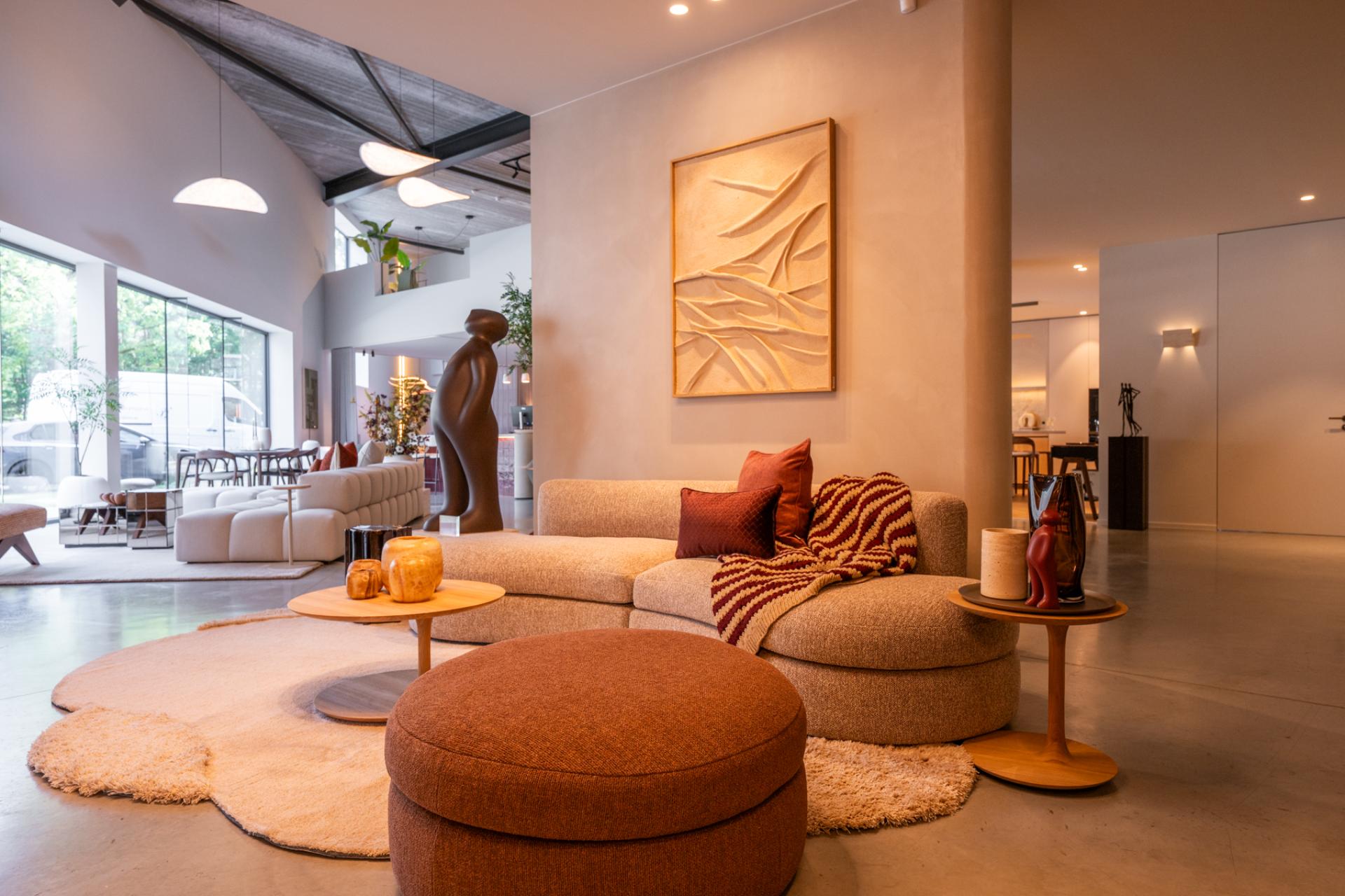 Sfeervolle zithoek met organische sofa, designmeubilair en warme aardetinten in luxe interieurshowroom
